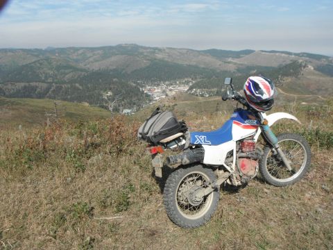 1987 Honda XL600R - A 1987 Honda XL600R motorcycle is parked on a scenic overlook, with a town visible in the valley below.