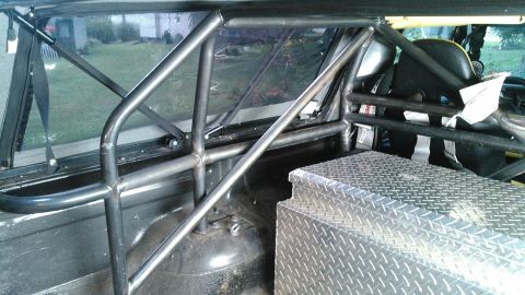 1978 Ford Bronco - The interior of a vehicle shows a custom roll cage and a diamond plate toolbox.