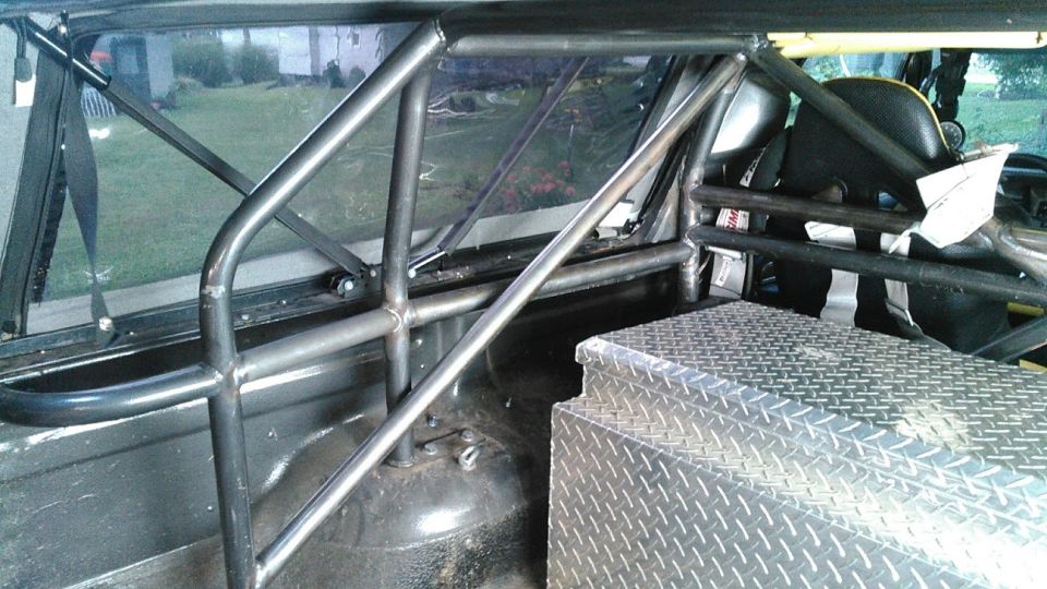 Interior view of a vehicle's roll cage, with a diamond plate toolbox in the foreground