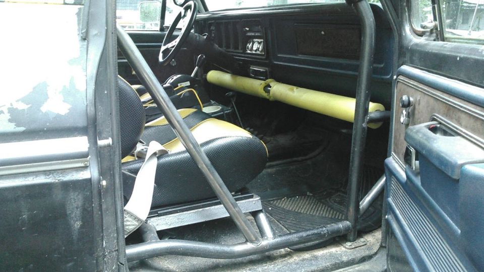 1978 Ford Bronco interior with black and yellow seats, roll cage, and yellow padding on the dashboard
