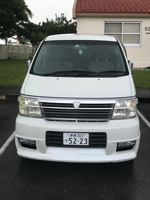 2002 Nissan Quest - A white minivan is parked in front of a building with a tiled roof.