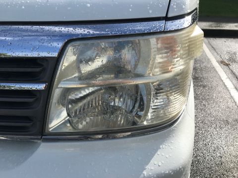 2002 Nissan Quest - The front passenger side headlight and grille of a white minivan are visible, with water droplets on the surface.