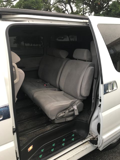 2002 Nissan Quest - The interior of a white minivan shows the second row of seats and the open sliding door.