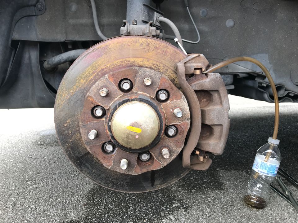 Brake caliper and rotor with fluid draining into a bottle
