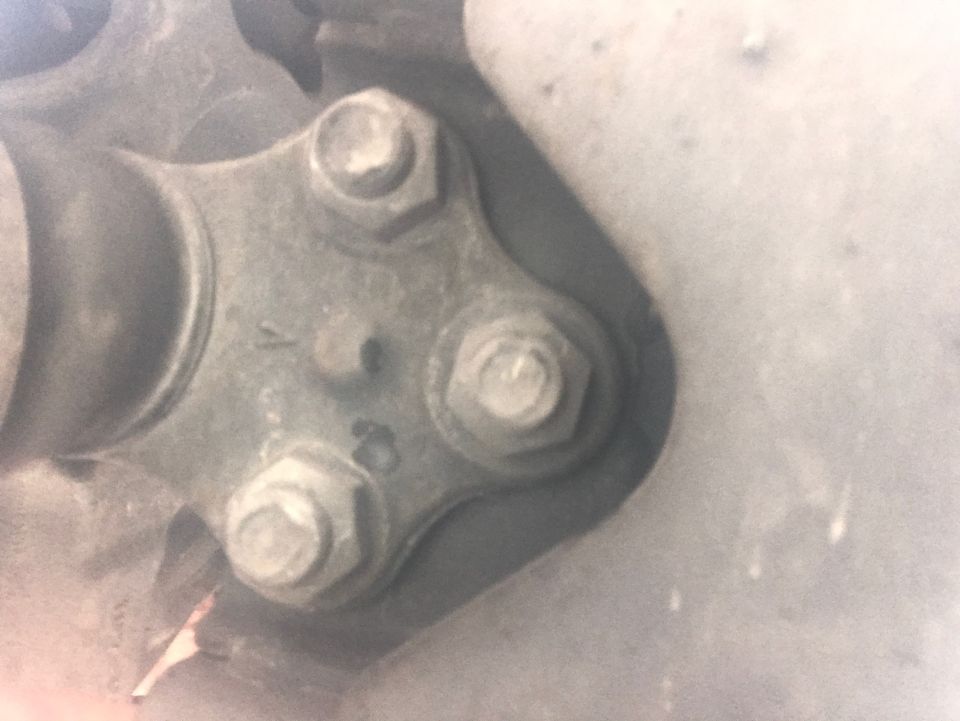 Close-up of a metal bracket with three bolts, part of a vehicle's suspension system