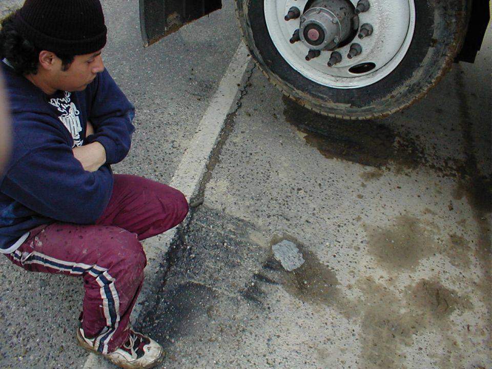 Person squatting by truck tire with puddle; Supermotors.net logo visible