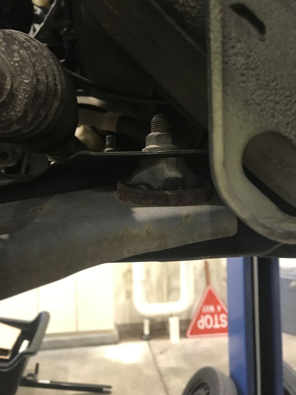Vehicle suspension with rubber bushing and bolt, automotive shop setting