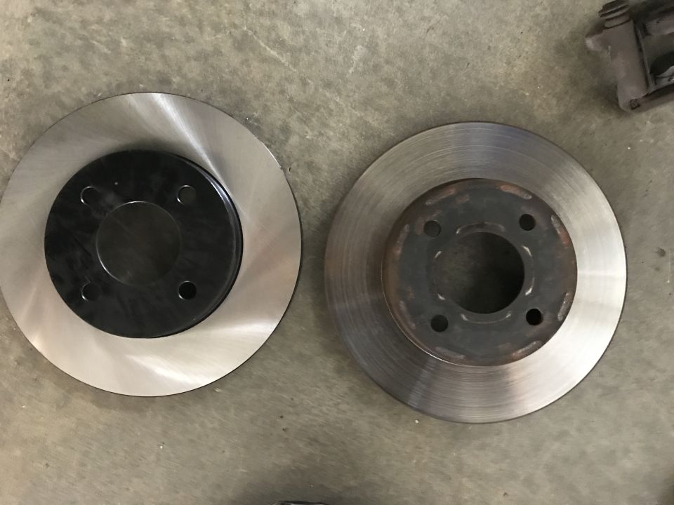 New and used brake rotors side-by-side on a concrete floor.