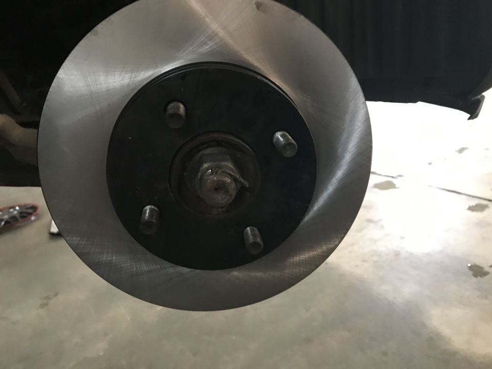 Close-up of a vehicle's brake rotor and hub assembly with lug nuts.