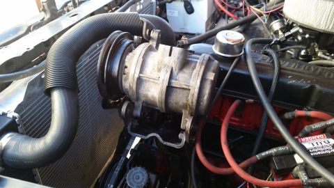 1985 Ford Bronco - Close-up view of the engine bay of a 1985 Ford Bronco, focusing on the air conditioning compressor and associated hoses. The engine feature…