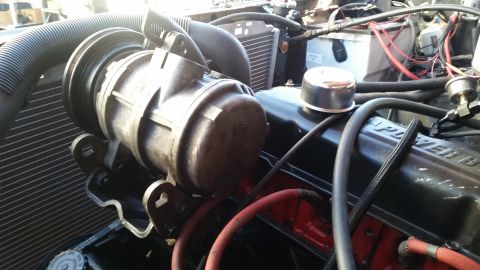 1985 Ford Bronco - Close-up view of the engine bay of a 1985 Ford Bronco, focusing on the air conditioning compressor and part of the engine block. The engine…