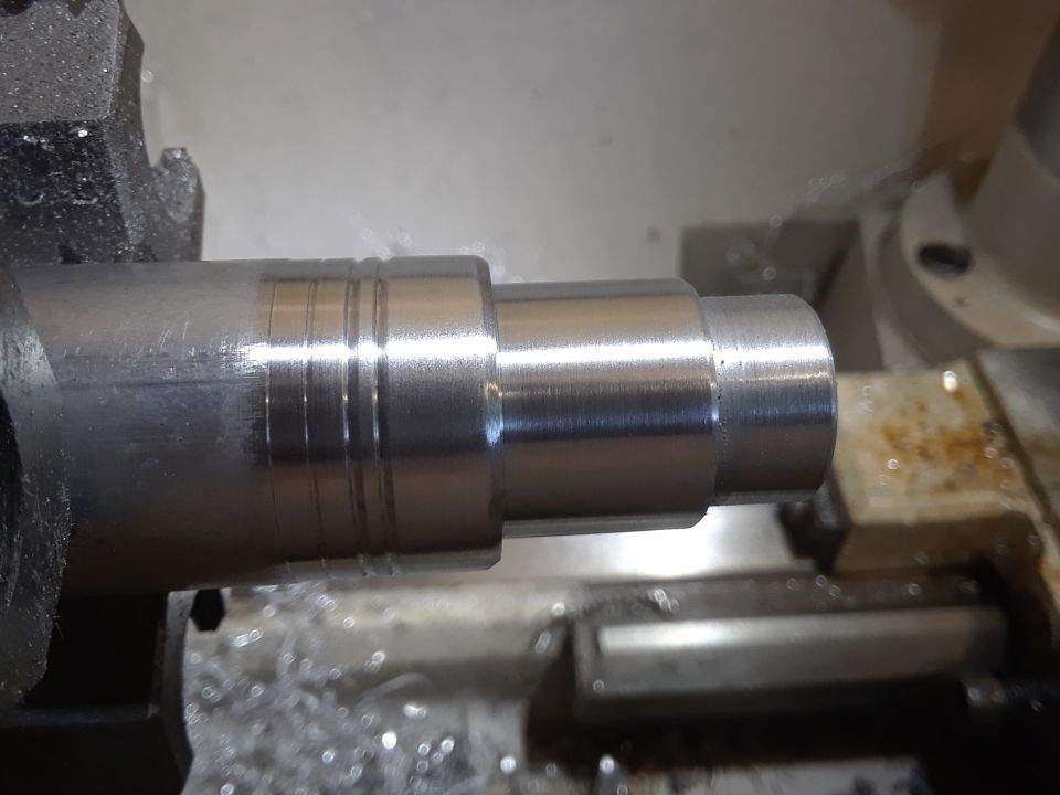 Close-up of a metal shaft being machined on a lathe with metal shavings.