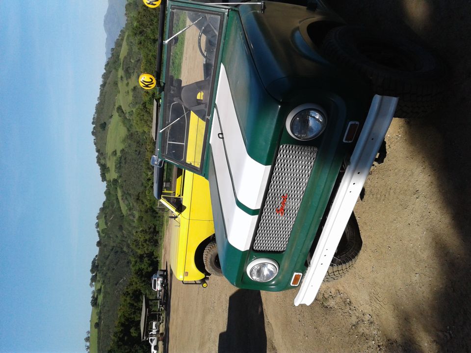 Green and white vintage SUV parked next to a yellow pickup truck