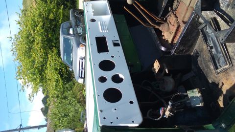 1991 Ford Bronco - A white painted dashboard panel with multiple circular cutouts is laid out in the bed of a dark green vehicle. A dark gray pickup truck is…