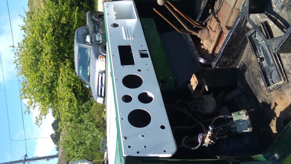 White painted dashboard panel with circular cutouts in a dark green vehicle bed.