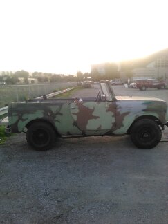 1991 Ford Bronco - A weathered, open-top SUV with a camouflage paint scheme is parked on a gravel lot. The vehicle appears to be a project in progress, with s…