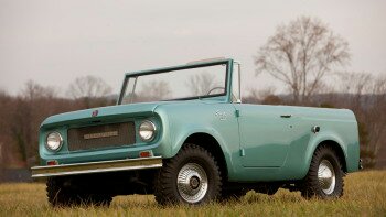 1991 Ford Bronco - A light teal International Harvester Scout 80 is shown from a 3/4 front angle in a grassy field with trees in the background. The convertib…