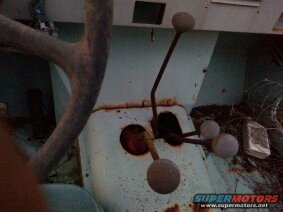 1991 Ford Bronco - The interior of a vintage vehicle shows a dashboard with two gear shift levers and a steering wheel column. The dashboard is painted a ligh…