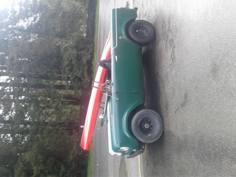 1991 Ford Bronco - A green vintage Jeep-like vehicle is parked on asphalt, with a red and white canoe strapped to its roof rack. The vehicle appears to be a c…