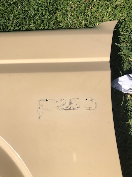 1981 Ford Bronco - A tan vehicle fender with the faded text "F250" visible. The fender is lying on a grassy area.
