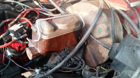 1985 Ford Bronco - The engine bay of a 1985 Ford Bronco shows a rusty brake master cylinder and various engine components, including spark plug wires and a di…