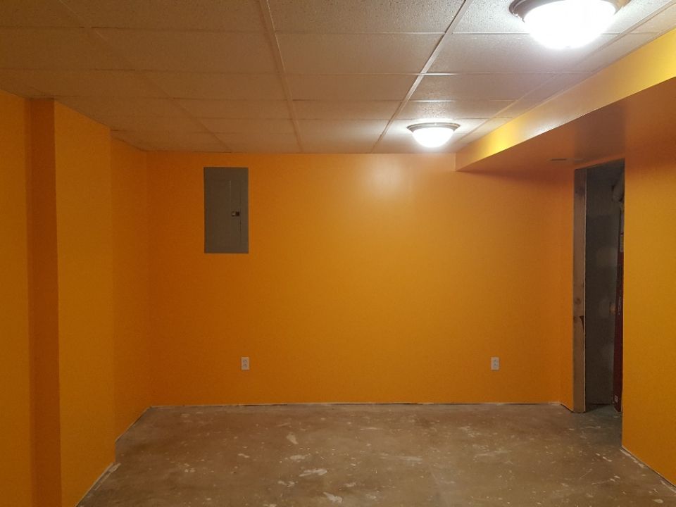 Empty room with orange walls and a concrete floor.