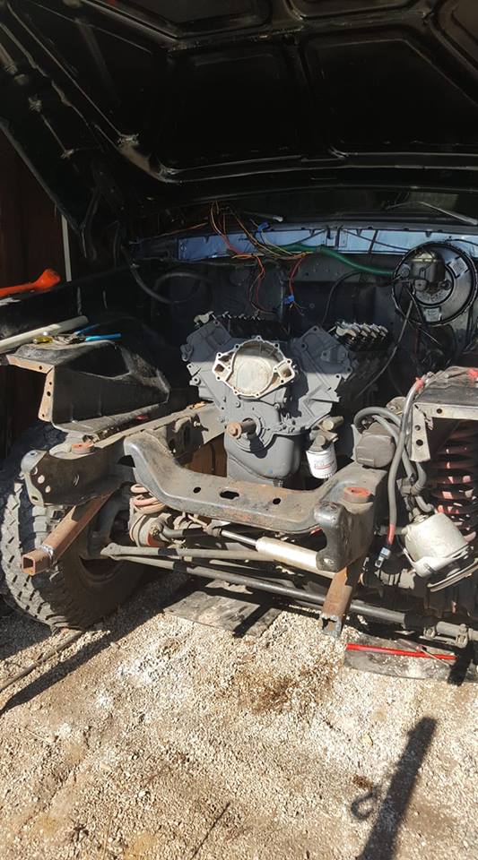 Vehicle engine bay with engine and wiring visible.