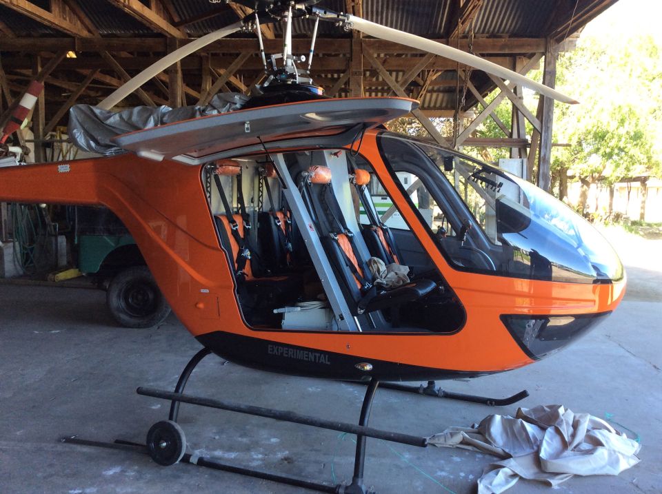 Orange experimental helicopter parked inside a wooden structure.
