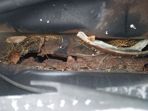 1994 Ford Bronco - Photograph of rusted vehicle metal with debris, not a technical document.
