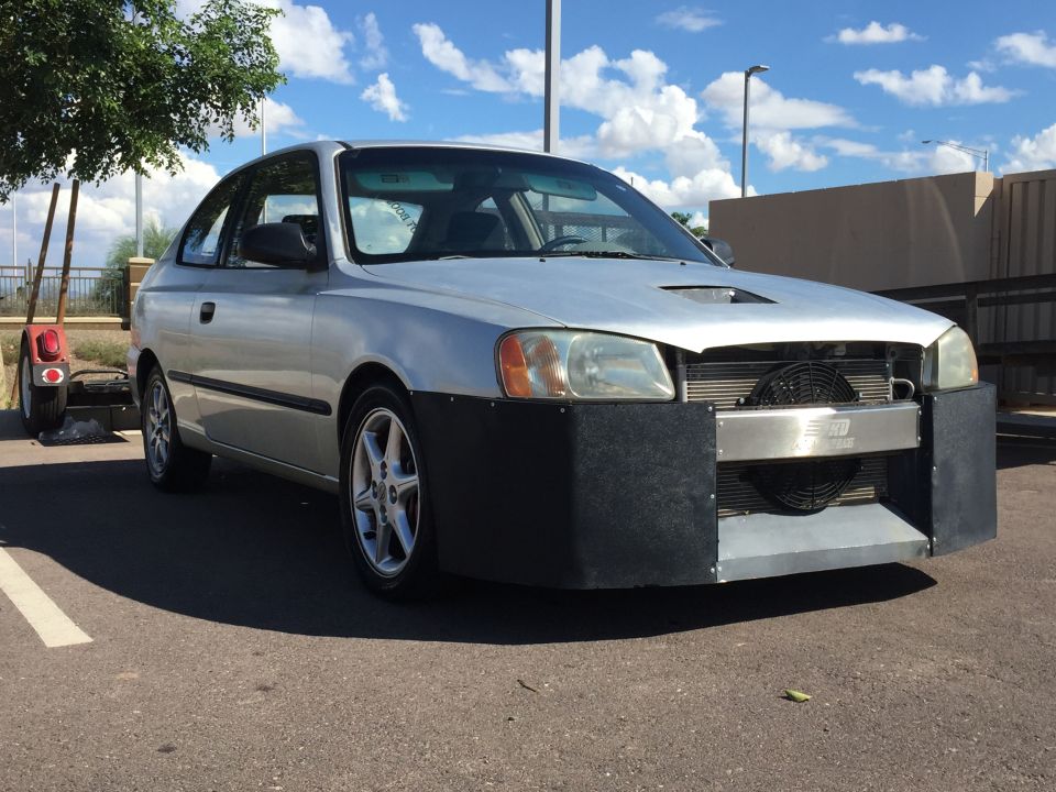 Silver 2001 Hyundai Accent hatchback with modified front bumper and visible intercooler and fan. Small traile…