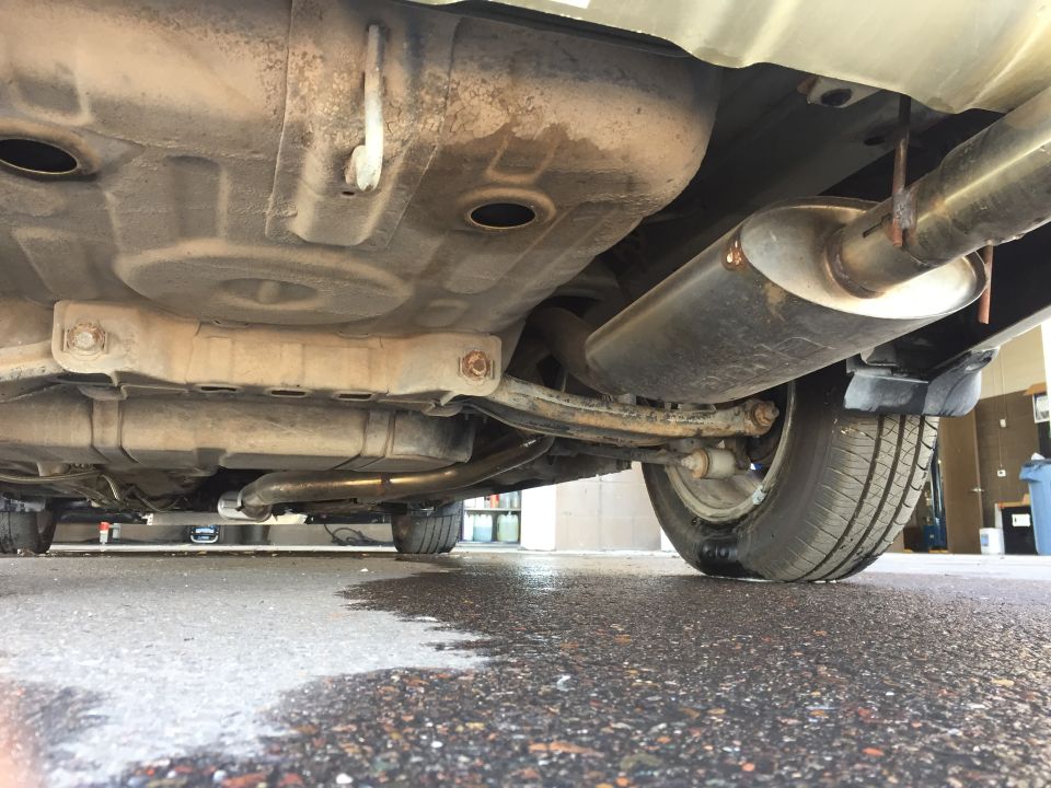 Underside of a car showing exhaust, suspension, and tire.