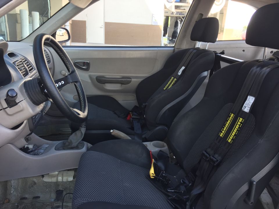 Interior of a 2001 Hyundai Accent with racing seats and harnesses.
