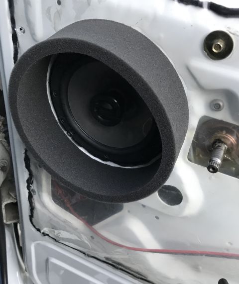 1995 Ford Bronco - A car door interior showing a speaker installed with a foam gasket. Red wiring is visible behind the speaker assembly.
