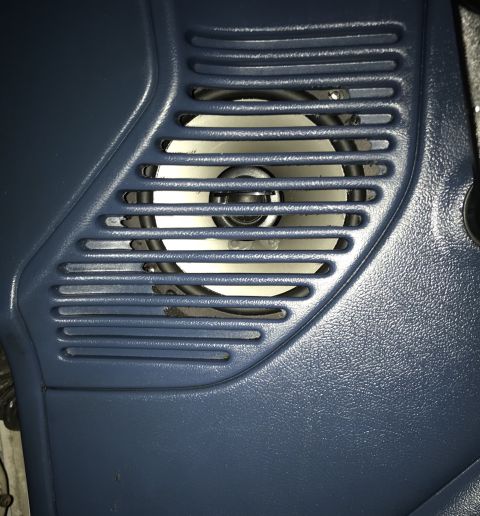 1995 Ford Bronco - A close-up view of a blue plastic door panel with a speaker grille and a visible speaker behind it. The speaker has a white cone and a blac…