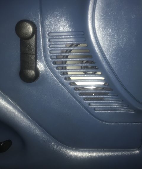 1995 Ford Bronco - A close-up interior shot shows a black window crank and a vent with horizontal slats on a blue door panel.