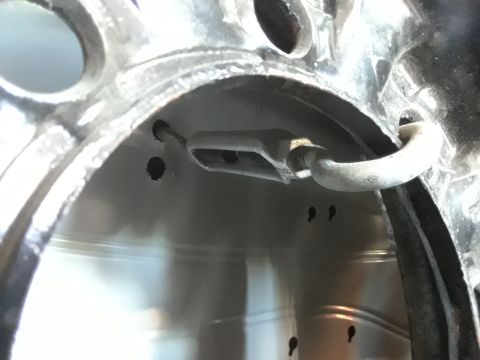 1999 Ford E250 - A close-up view shows a turnbuckle attached to a metal loop on the interior of a vehicle's wheel well. Several small holes are visible in t…