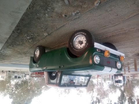 1991 Ford Bronco - A green vintage SUV with white racing stripes on the front is parked outdoors. The vehicle has a spare tire mounted on the rear and KC ligh…