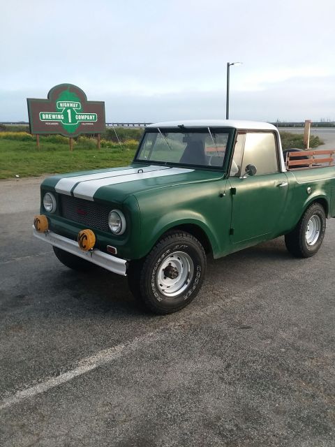 1991 Ford Bronco - A green International Harvester Scout pickup truck with white racing stripes on the hood is parked in front of a sign for Highway 1 Brewing…