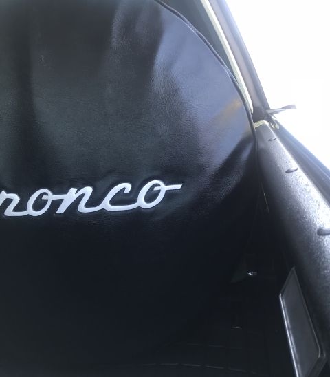 1995 Ford Bronco - The interior of a 1995 Ford Bronco features the model name embroidered on a black seat cover.
