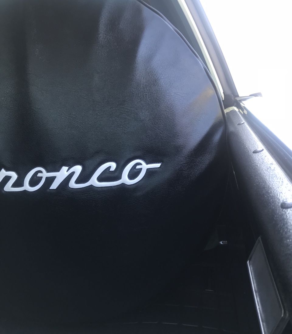 Interior shot of a 1995 Ford Bronco showing the word Bronco embroidered on the black upholstery
