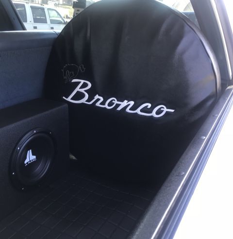 1995 Ford Bronco - Spare tire cover with Bronco branding and a JL Audio subwoofer are visible in the cargo area of a vehicle.