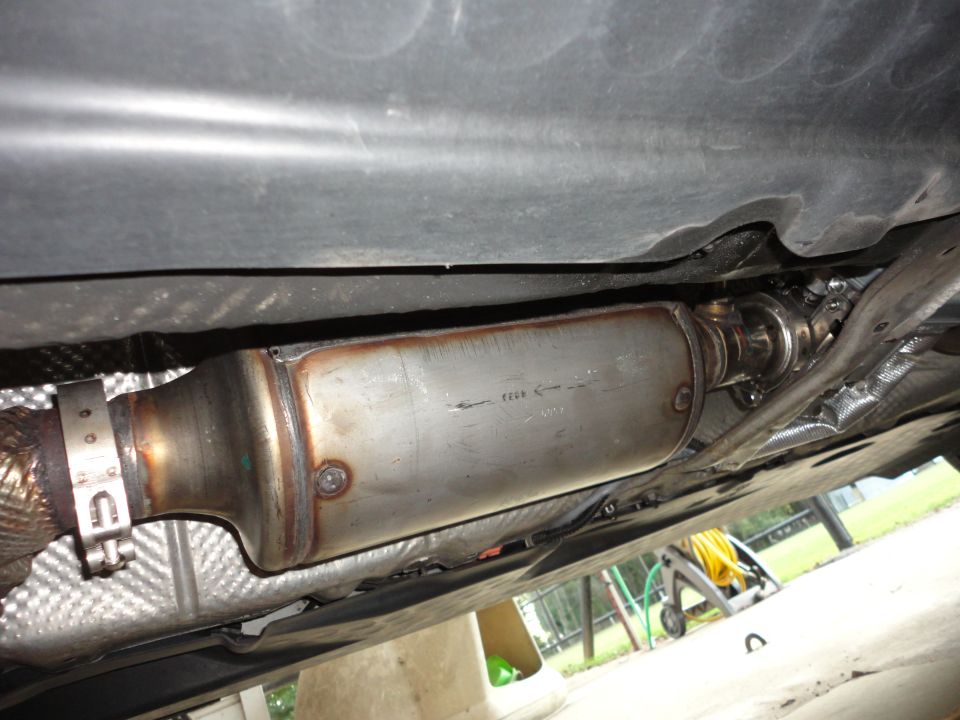Underside view of a car showing stainless exhaust DPF canister with band clamp and heat shields