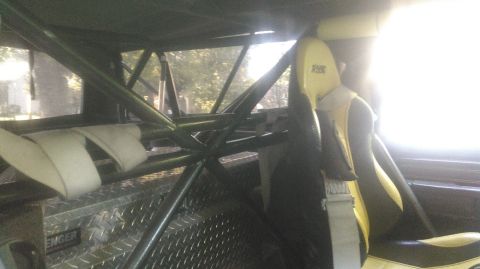 1978 Ford Bronco - Interior view of a vehicle's roll cage and racing seat, with a toolbox in the background.