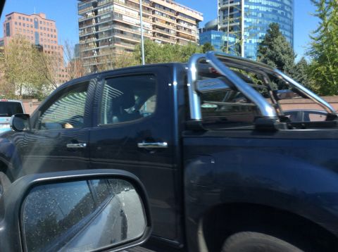 1992 Ford Bronco - Pickup truck with chrome roll bar driving on a sunny day.