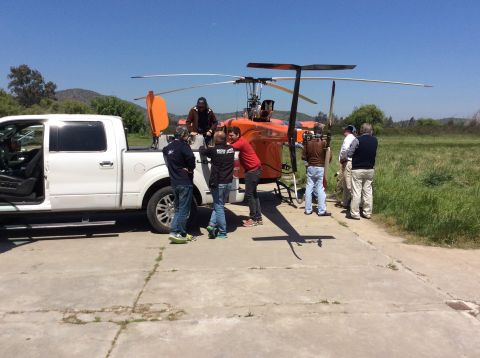 1992 Ford Bronco - A group of people gather around a helicopter and a pickup truck on a sunny day.