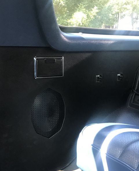 1995 Ford Bronco - Close-up of a vehicle's interior door panel, showing a speaker and a small storage compartment.