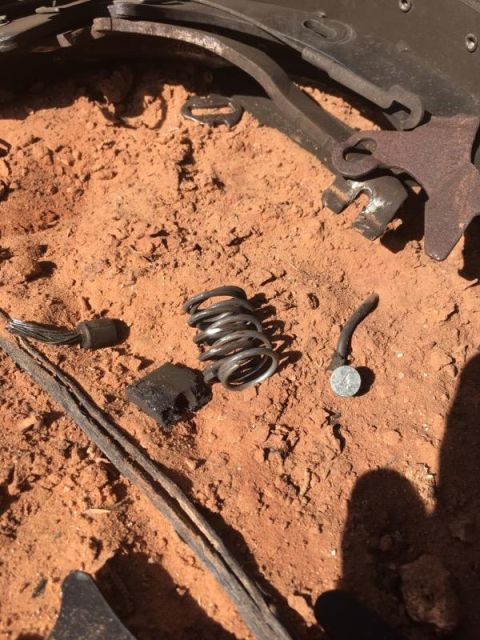 1995 Ford Bronco - Various brake components and debris are scattered on the dusty ground, suggesting a vehicle part failure.