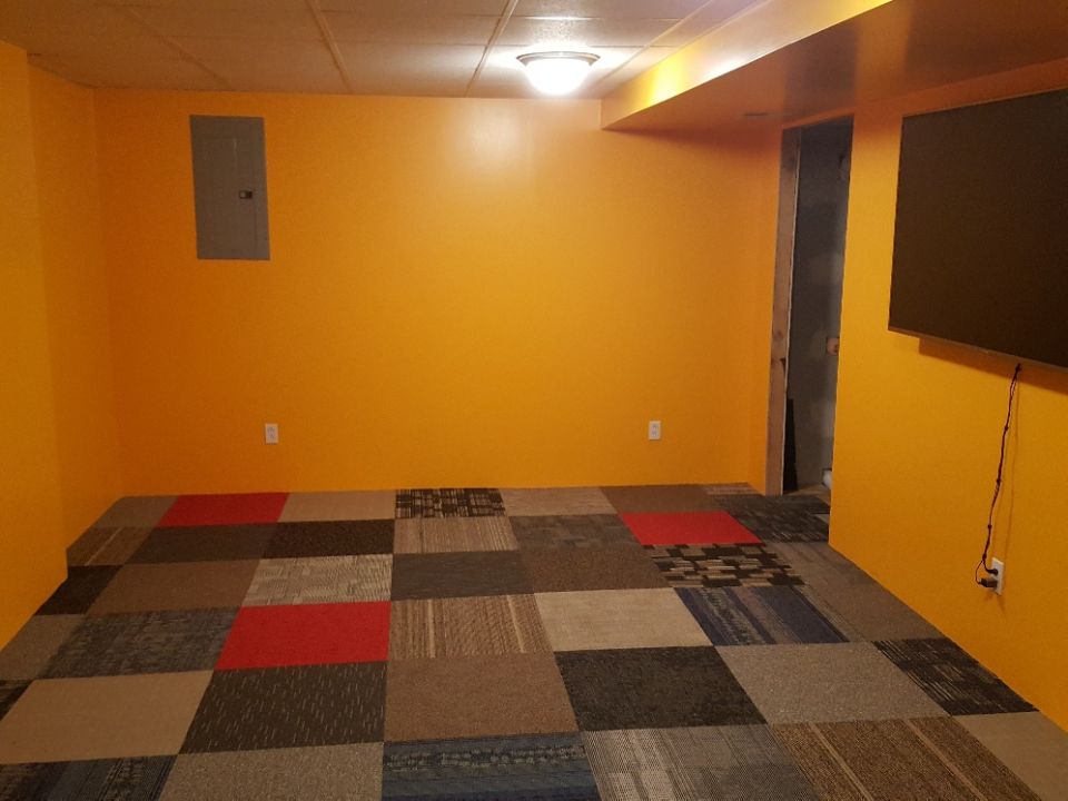 room with orange walls, tiled floor, and a TV mounted on the wall