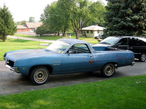 1971 Ford Ranchero - A blue 1970 Ford Ranchero pickup truck is seen parked on a driveway, with a black van behind it.