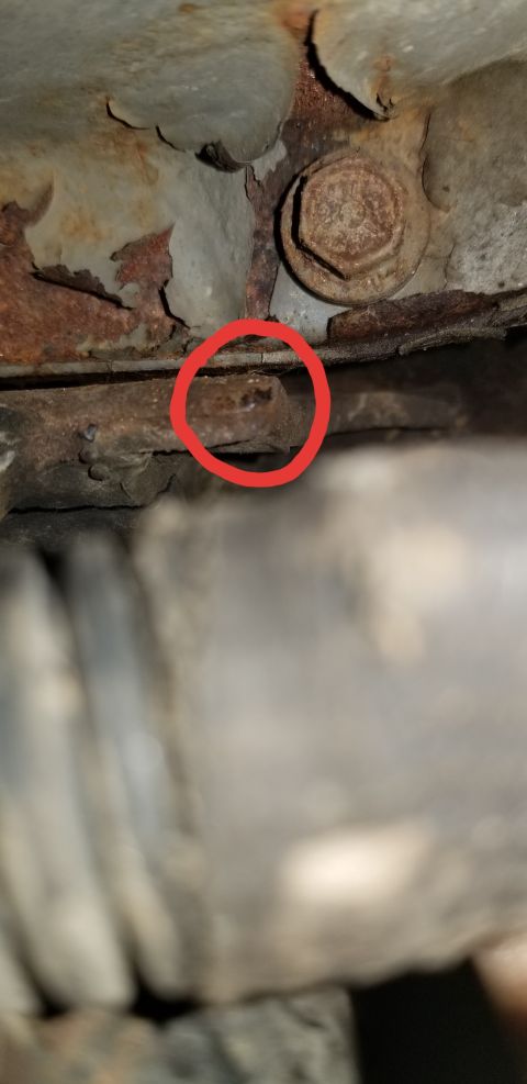 1995 Ford Bronco - Detail of a corroded vehicle undercarriage, showing significant rust and a bolt head.